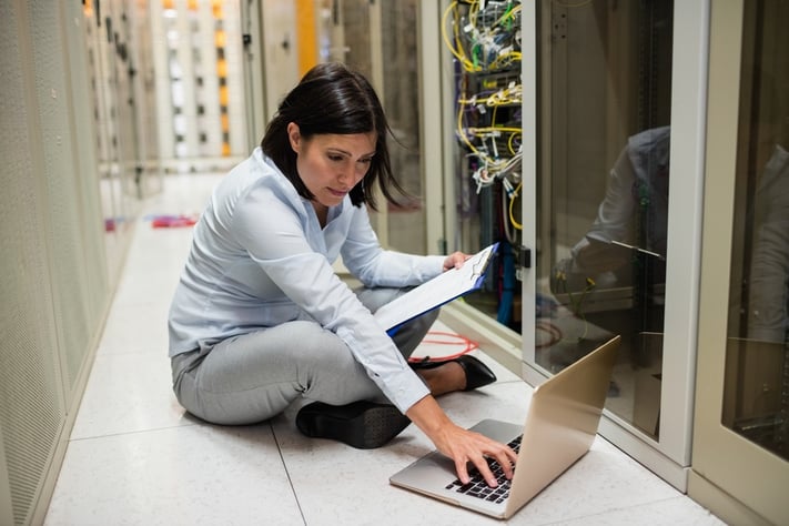 Technician checking clipboard while working on laptop.jpeg